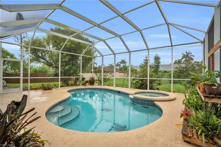 View of swimming pool with a patio, an in ground hot tub, and glass enclosure