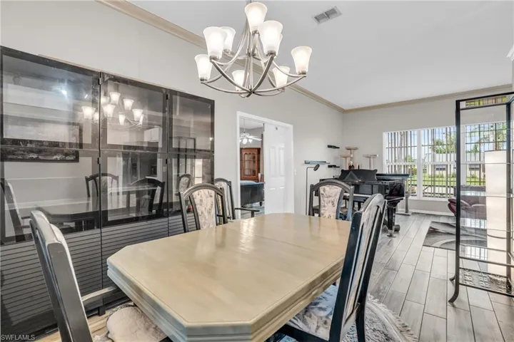 Dining area featuring crown molding, wood-type flooring, and a notable chandelier