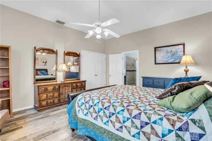Bedroom featuring a closet, ensuite bathroom, ceiling fan, and light wood-type flooring