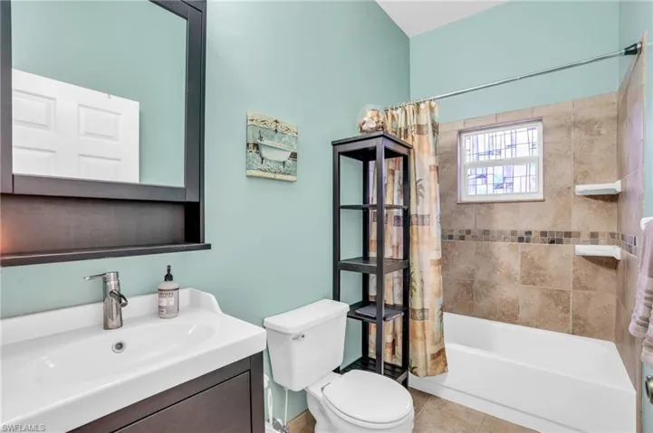Full bathroom featuring tile patterned floors, toilet, vanity, and shower / tub combo with curtain