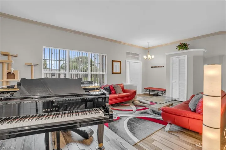 Living room featuring wood-type flooring, a notable chandelier, and ornamental molding