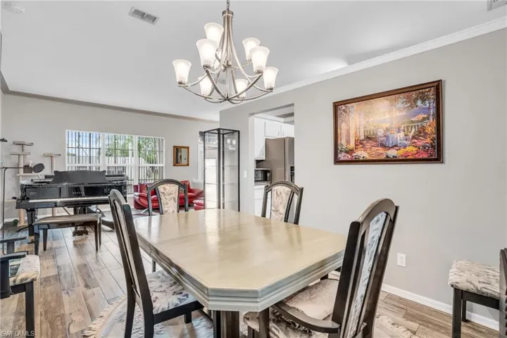 Dining room with hardwood / wood-style flooring, crown molding, and a chandelier