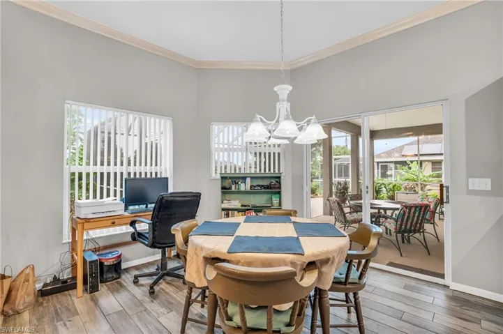 Dining space with a notable chandelier, wood-type flooring, crown molding, and a high ceiling