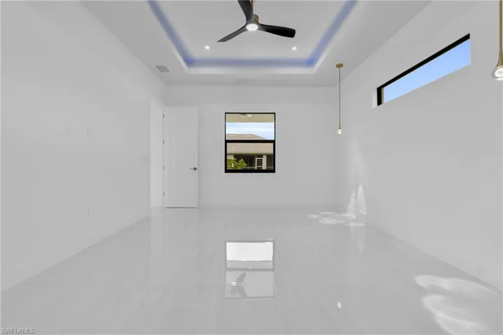 Spare room featuring a ceiling fan, a tray ceiling, and light tile patterned floors