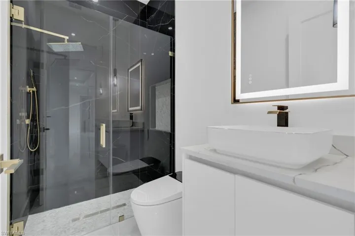 Bathroom featuring vanity and a marble finish shower