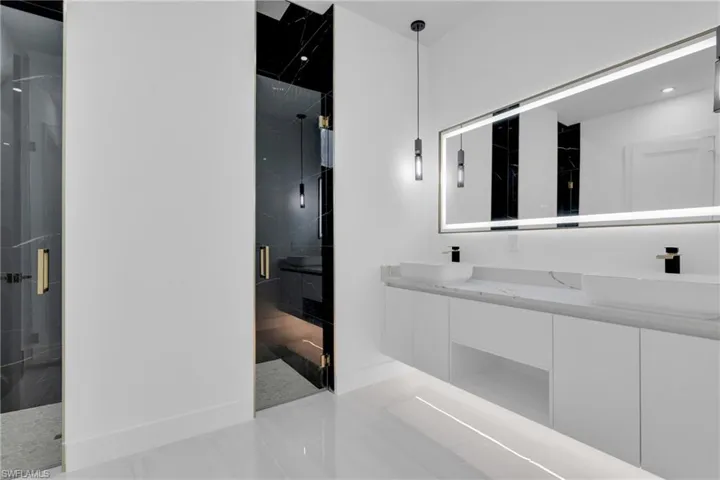 Full bathroom featuring double vanity, a marble finish shower, and light tile patterned flooring