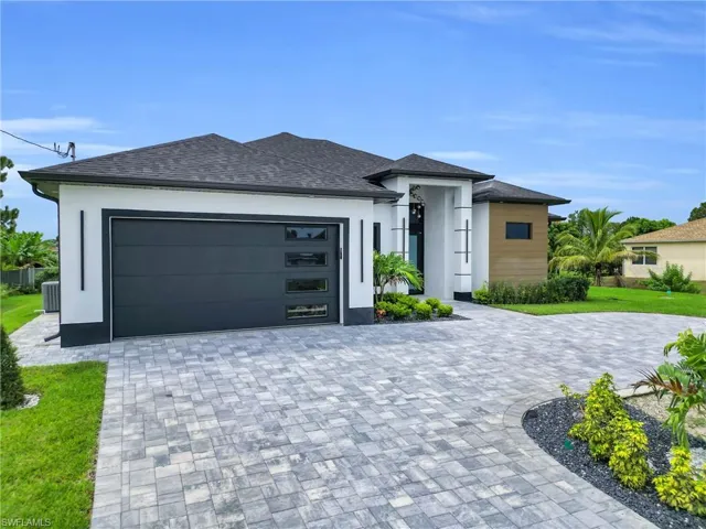 Prairie-style house with an attached garage, decorative driveway, stucco siding, a front yard, and a shingled roof