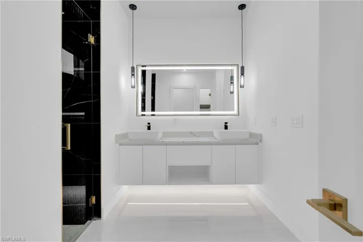 Bathroom featuring a marble finish shower, double vanity, and light tile patterned flooring