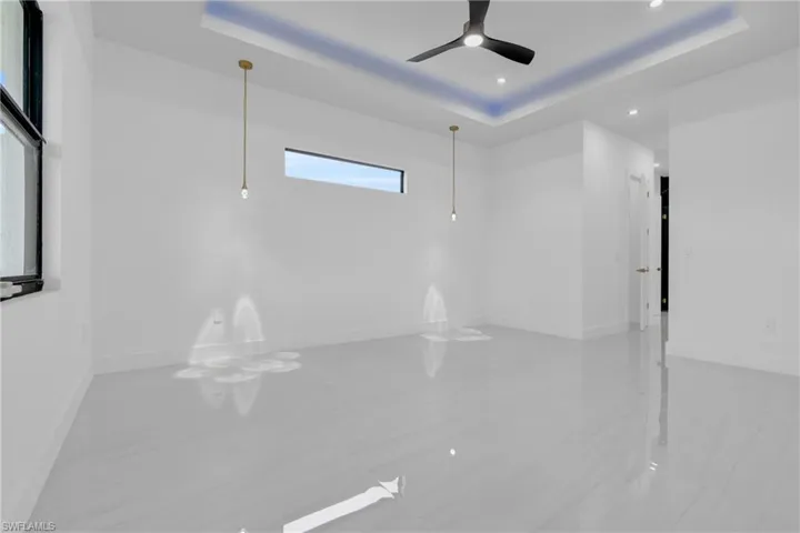 Empty room with a raised ceiling, recessed lighting, and a ceiling fan