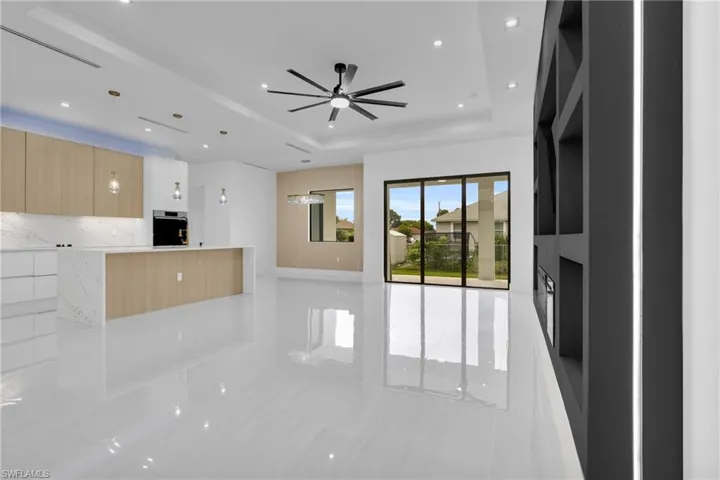Unfurnished living room featuring a tray ceiling, light tile patterned flooring, recessed lighting, and ceiling fan