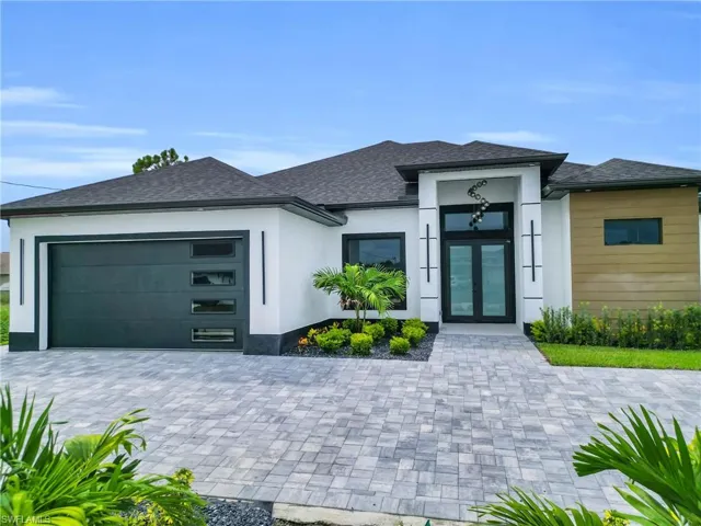 Prairie-style house featuring stucco siding, roof with shingles, a garage, decorative driveway, and french doors