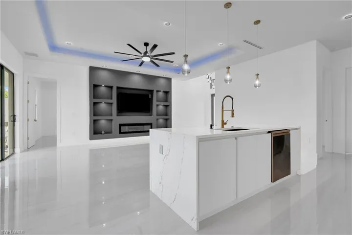 Kitchen with white cabinets, decorative light fixtures, modern cabinets, a raised ceiling, and light stone counters
