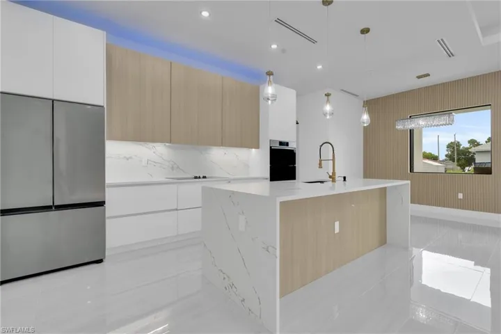 Kitchen featuring appliances with stainless steel finishes, pendant lighting, light brown cabinetry, light tile patterned flooring, and recessed lighting