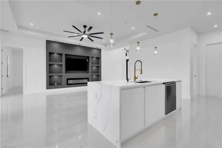 Kitchen with modern cabinets, white cabinets, pendant lighting, recessed lighting, and light stone counters