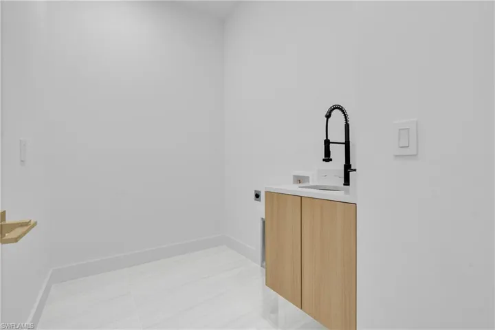 Laundry area featuring electric dryer hookup, light tile patterned flooring, washer hookup, and cabinet space