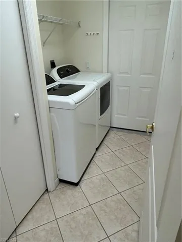 Laundry area featuring newer washing machine and clothes dryer and light tile patterned flooring
