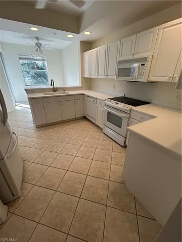 Kitchen with stove, light countertops, a peninsula, newer appliances and recessed lighting