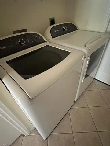 Laundry area featuring light tile patterned flooring and newer appliances washing machine and clothes dryer
