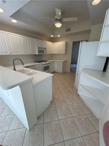 Kitchen featuring white cabinets, light countertops, newer appliances and ceiling fan