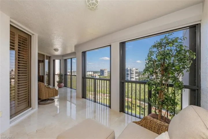 Sunroom / solarium with a textured ceiling, floor to ceiling windows, and a city view