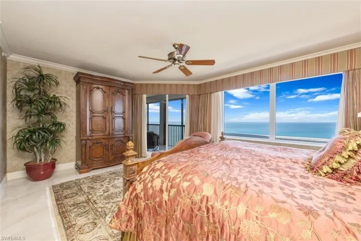 Unfurnished bedroom featuring access to outside, ornamental molding, a ceiling fan, wallpapered walls, and a water view