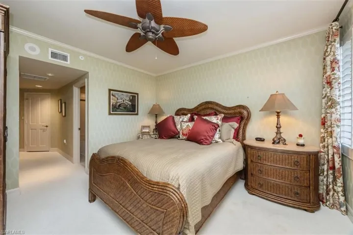 Carpeted bedroom with crown molding, wallpapered walls, and a ceiling fan