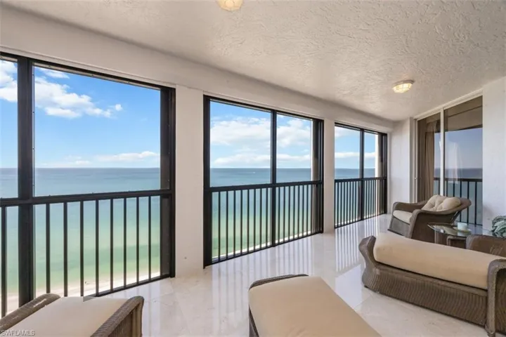 Sunroom with a textured ceiling, a water view, marble tiled flooring, and expansive windows