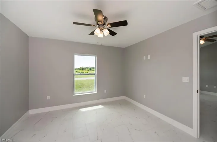 Unfurnished room with ceiling fan and light marble finish flooring