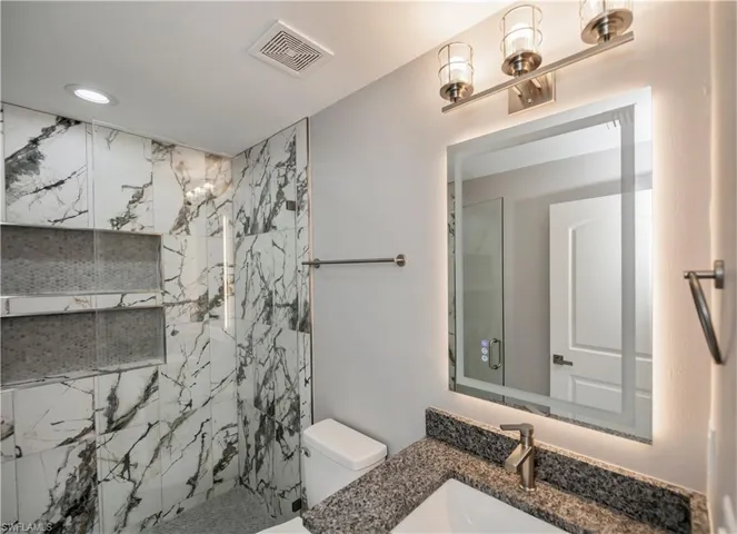 Full bathroom with a marble finish shower and vanity