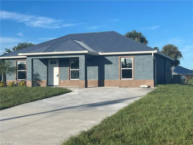 View of front of home with stucco siding, a front lawn, and a metal roof