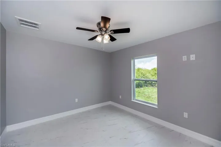 Unfurnished room featuring light marble finish flooring and ceiling fan