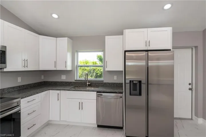Kitchen with light marble finish flooring, appliances with stainless steel finishes, recessed lighting, and white cabinetry