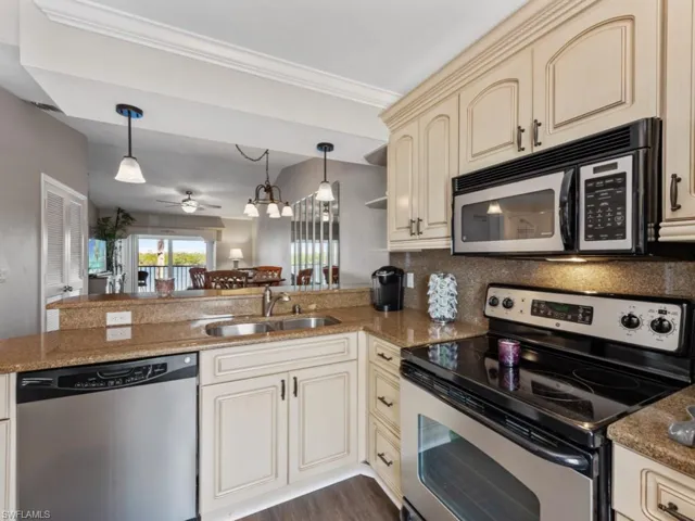 Kitchen with a peninsula, a ceiling fan, a sink, stainless steel appliances, and cream cabinets