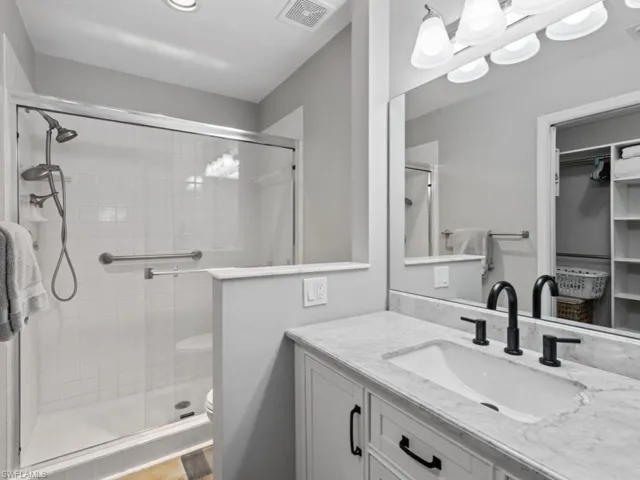 Full bathroom featuring toilet, a stall shower, vanity, and visible vents