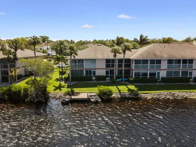 Rear view of property with a water view and a lawn
