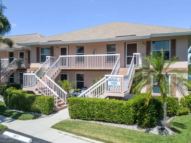 View of property featuring stairs and uncovered parking