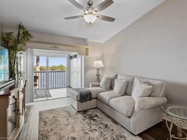 Living room featuring a water view, lofted ceiling, a ceiling fan, and wood finished floors