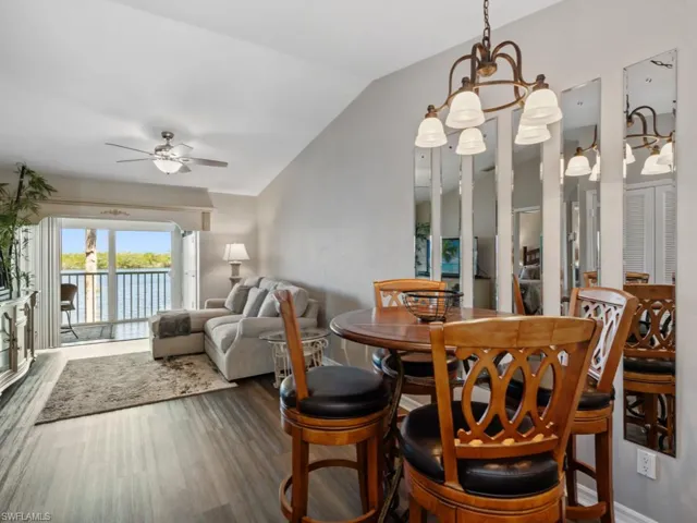 Dining area with wood finished floors, a ceiling fan, lofted ceiling, and a water view