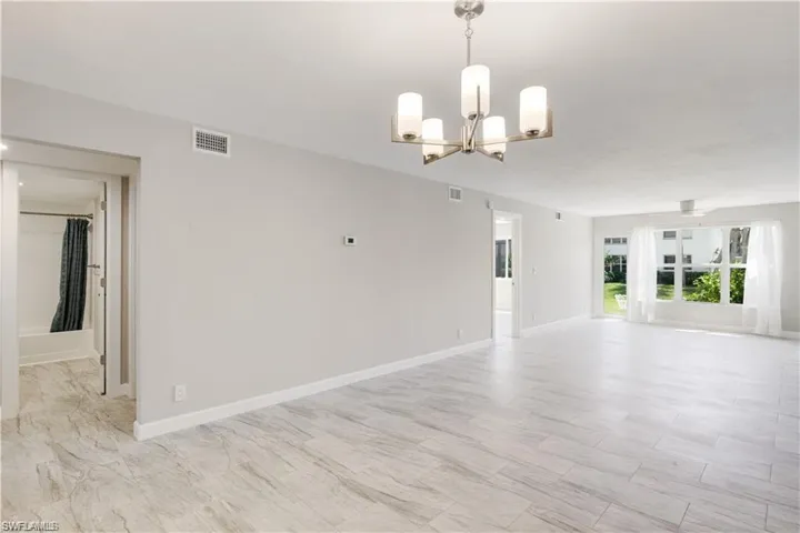 Empty room with a notable chandelier and light tile patterned floors