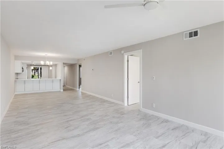 Unfurnished living room featuring ceiling fan with notable chandelier