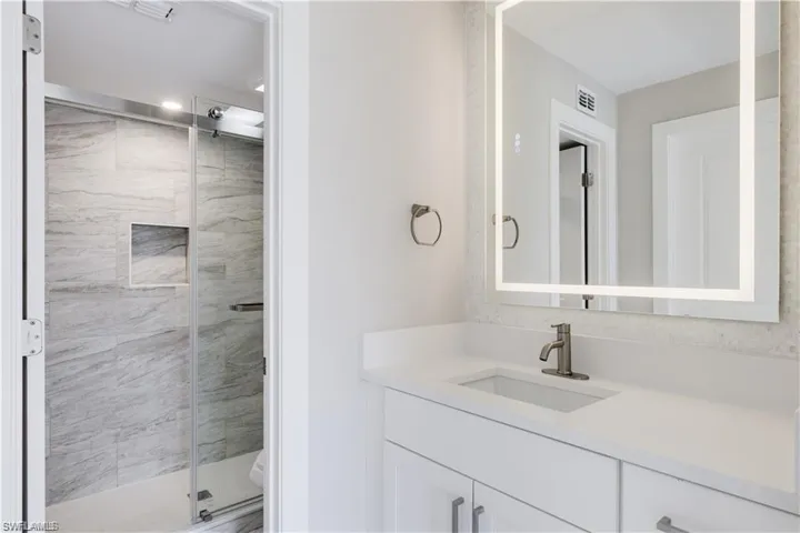 Bathroom featuring a shower with shower door, vanity, and toilet