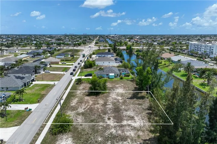 Aerial perspective of suburban area featuring a large body of water and property boundaries highlighted