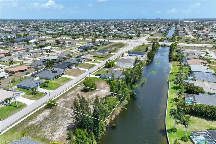 Aerial view of residential area with a nearby body of water and property boundaries highlighted