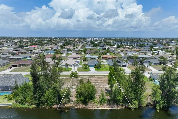 Aerial view of residential area featuring property parcel outlined and a large body of water