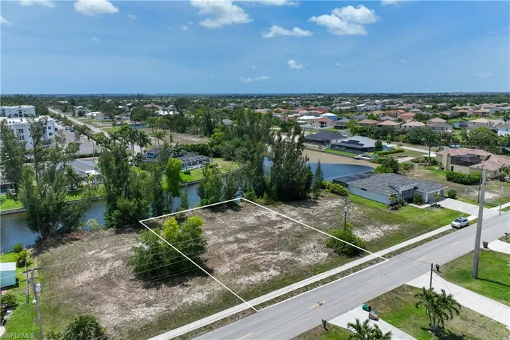 Aerial perspective of suburban area featuring a large body of water and property parcel outlined