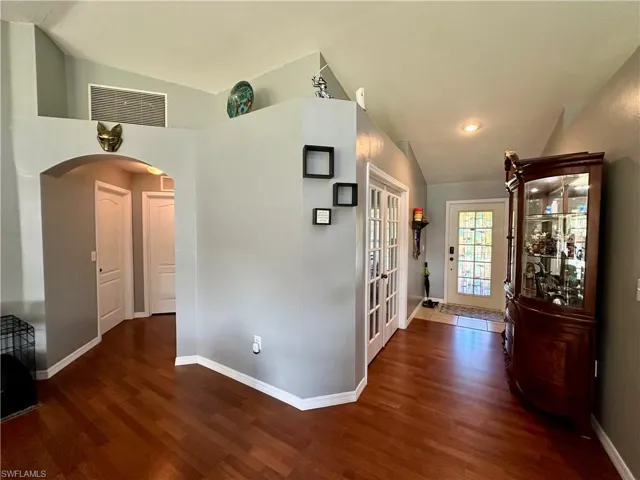 Corridor featuring french doors, dark hardwood / wood-style floors, and vaulted ceiling