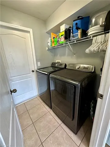 Clothes washing area featuring light tile patterned flooring and independent washer and dryer
