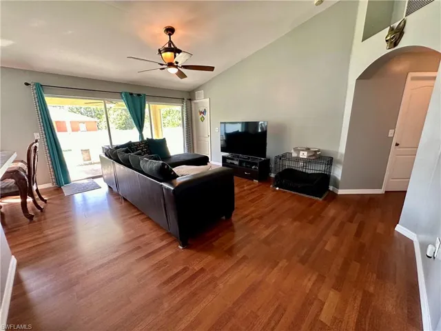 Living room featuring ceiling fan, vaulted ceiling, and dark hardwood / wood-style flooring