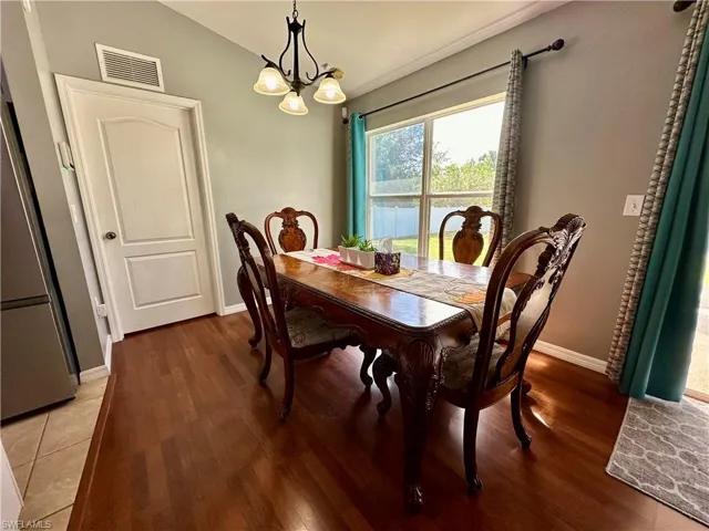 Dining space with vaulted ceiling, a chandelier, and wood-type flooring