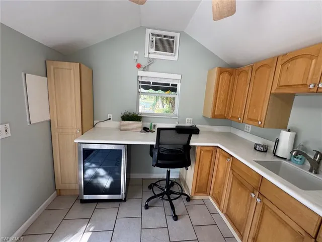 Tiled office with ceiling fan, sink, built in desk, wine cooler, and lofted ceiling